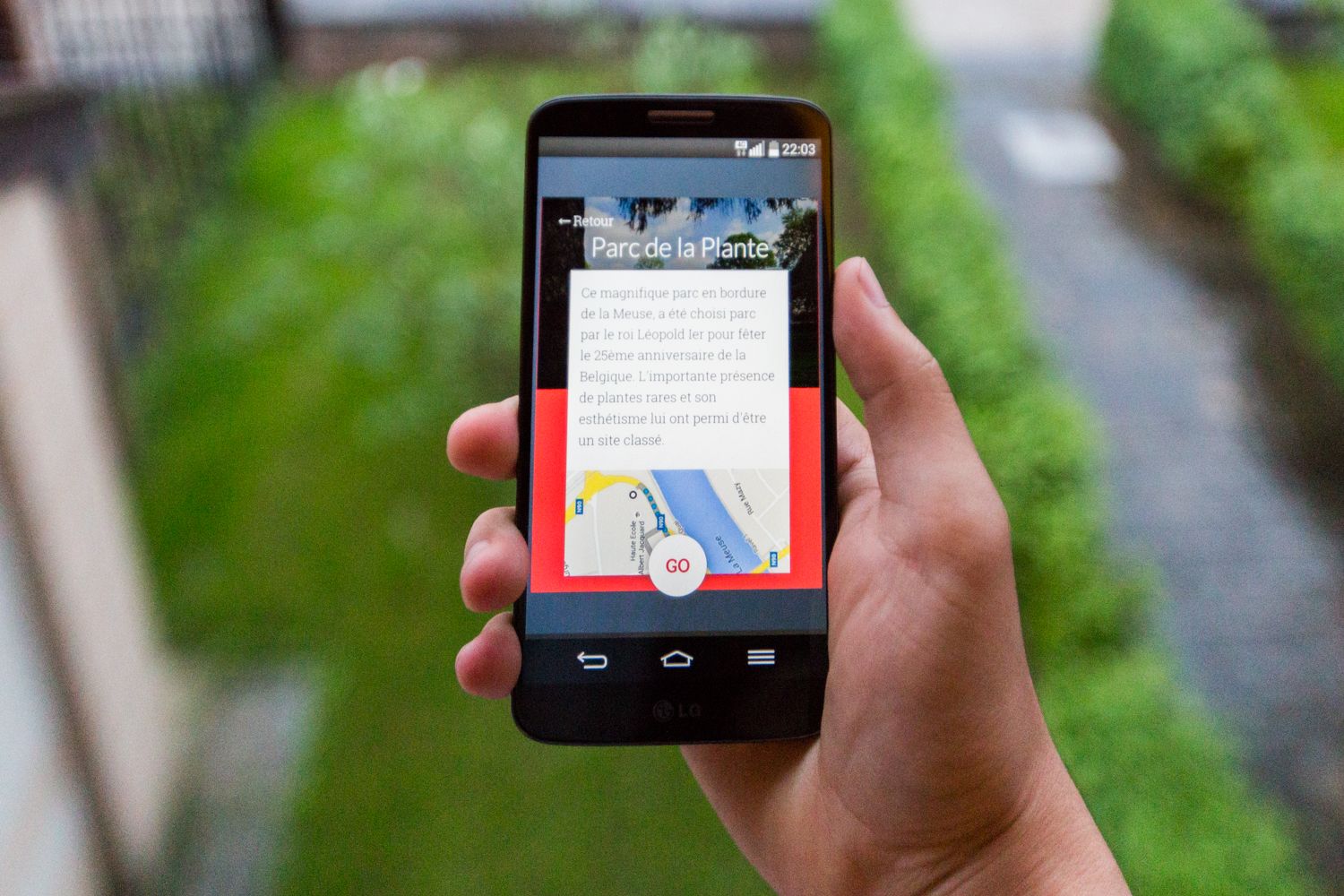 Photo de l'écran sur la page descriptive du parc de la plante, tenu dans une main à l'extérieur.